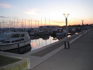 A marina with boats docked, a walkway, and a street lamp. - Apartments Amalia (Zadar)