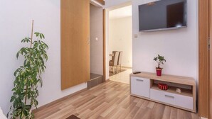 A modern living room with a sliding door, a flat-screen TV, a wooden cabinet, and a potted plant. - Apartment Niko (Sibenik)