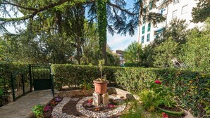 A garden with a stone pathway, potted plants, and a gate. - Green Terrace Apartment I (Dubrovnik)