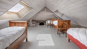 Un dormitorio pequeño estilo ático con dos camas de madera, un escritorio y una silla.