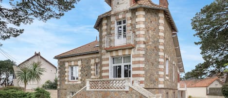 A stone building with a balcony, a staircase, and a clear sky.