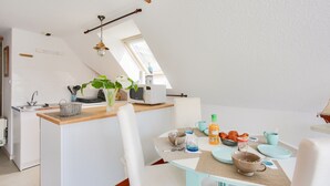 Una cocina moderna con comedor, que incluye una isla central, armarios blancos y un tragaluz.