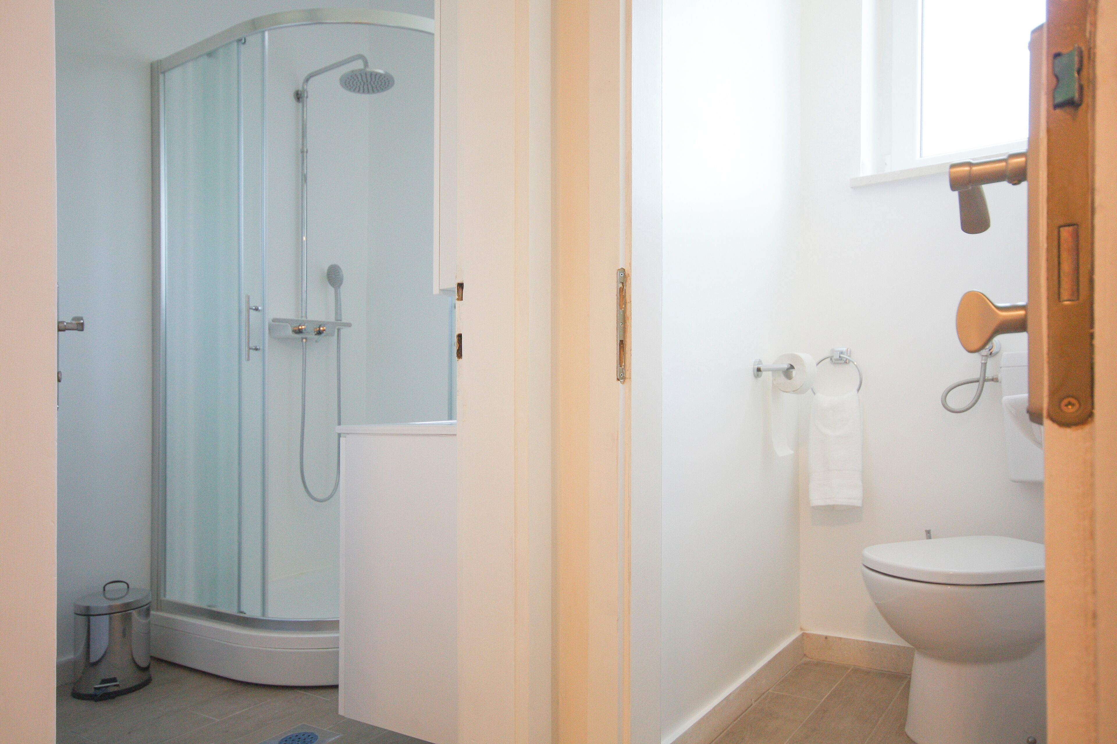 A bathroom with a shower, toilet, and a window.