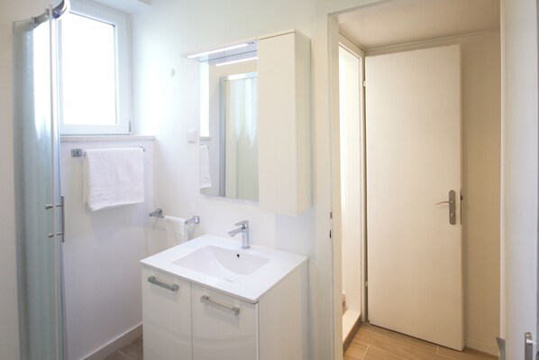 A bathroom with a white sink, mirror, and towel hanging on the wall.