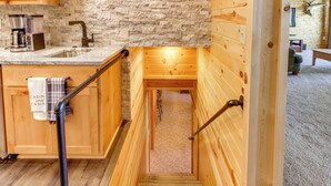A wooden cabin interior with a kitchen area, a staircase, and a view into the living space. - Private Lakefront Emily Home w/ Yard & Fire Pit! (Emily)