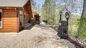 A wooden cabin with a brick patio, outdoor seating, and a bell system. - Private Lakefront Emily Home w/ Yard & Fire Pit! (Emily)