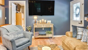Een woonkamer met een grijze fauteuil, een houten salontafel en een beige bank.