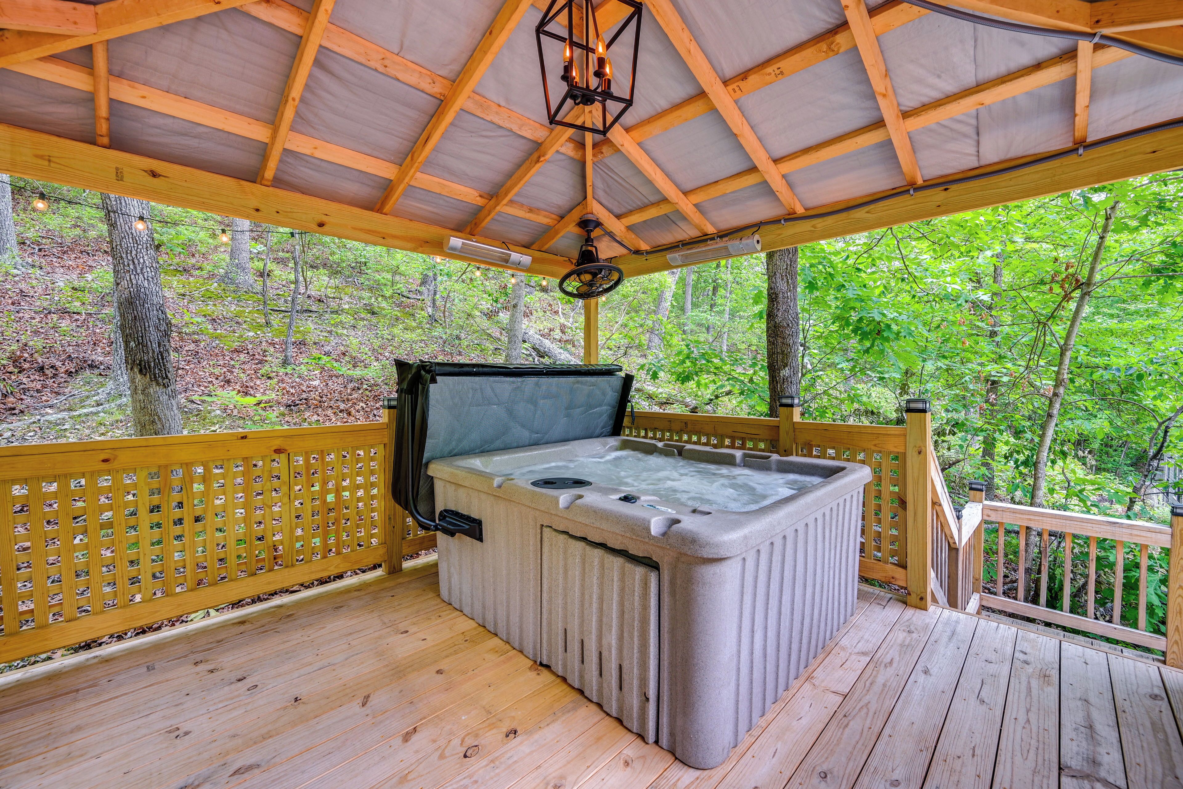 Un jacuzzi en una terraza de madera con barandilla y una cubierta superior.