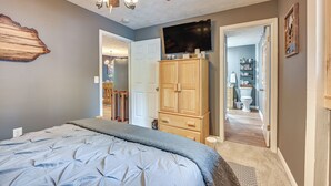 Een slaapkamer met een bed, een houten kledingkast en een televisie aan de muur.