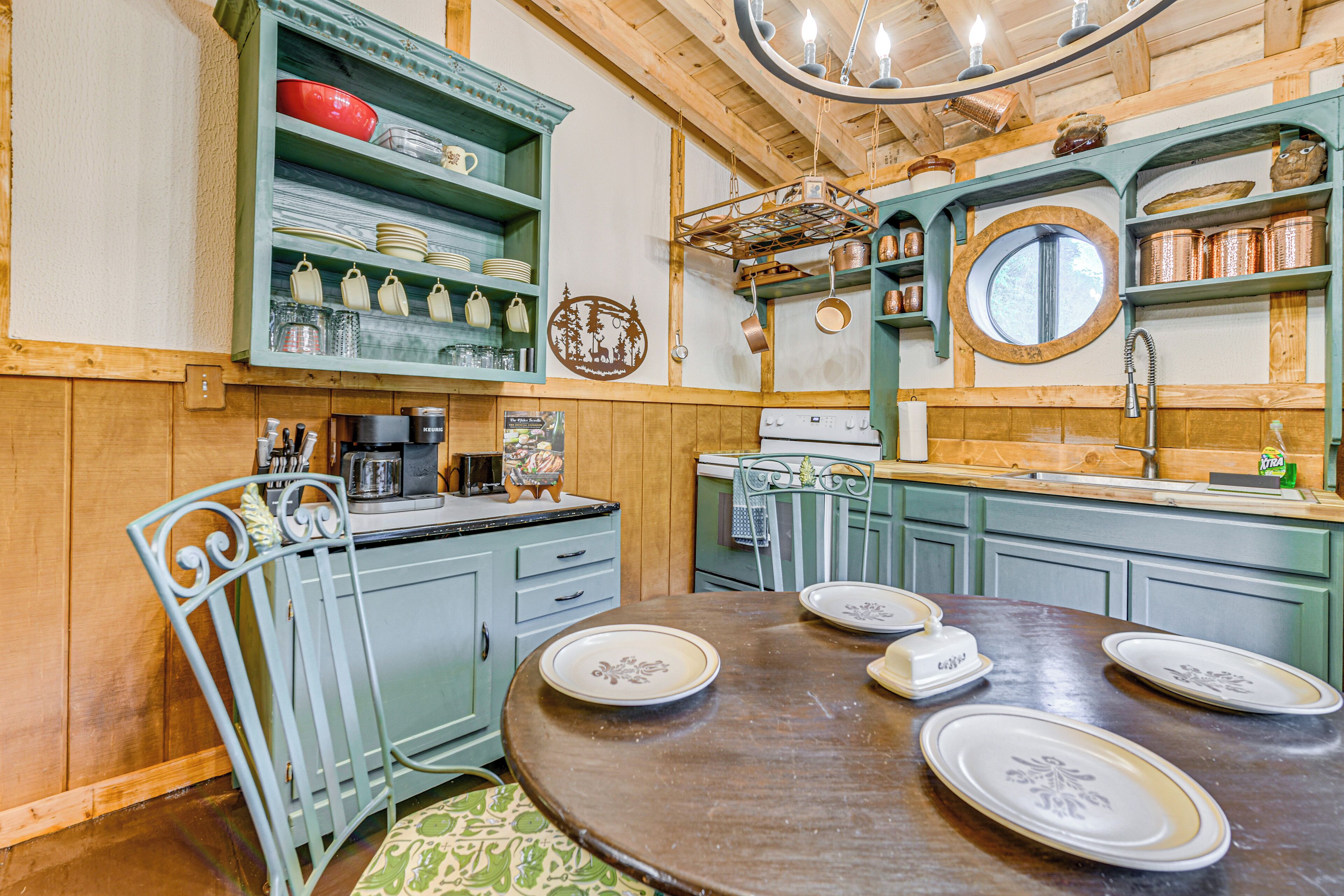 A kitchen with wooden cabinets, a round dining table with plates, and a hanging pot rack.