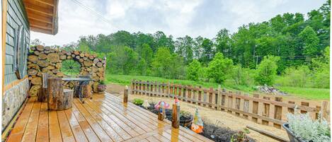 A wooden deck with a stone wall, potted plants, and a wooden fence.