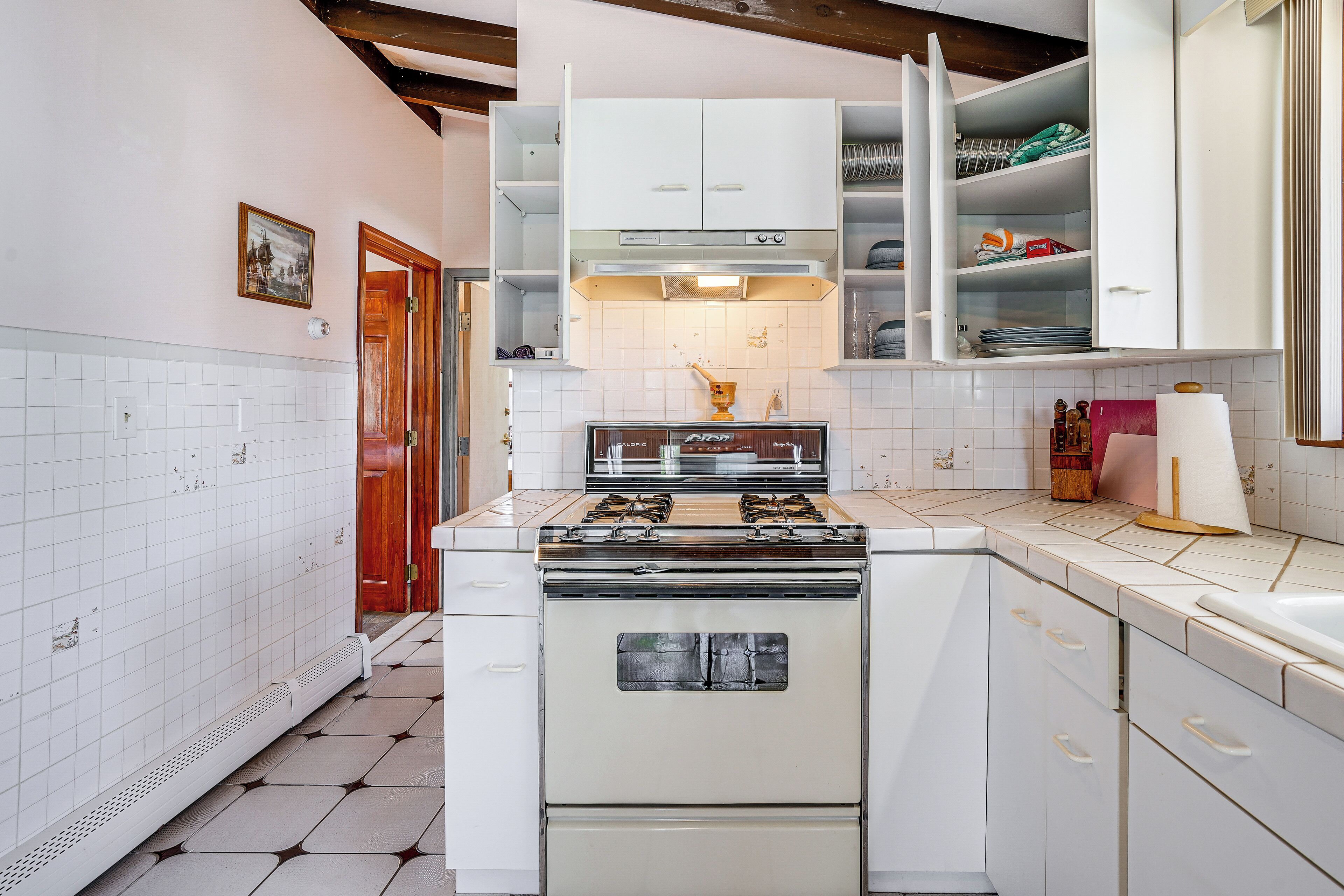 A kitchen with white cabinets, a stove, and a tiled backsplash.