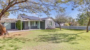 A house with a covered porch, a solar panel roof, and a well-maintained lawn. - Bar & Fire Pit: Pet-friendly Phoenix 'La Casita' (Phoenix)