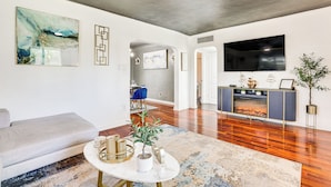 A modern living room with a sofa, a coffee table with decorative items, a fireplace, and a flat-screen TV mounted on the wall. - Bar & Fire Pit: Pet-friendly Phoenix 'La Casita' (Phoenix)