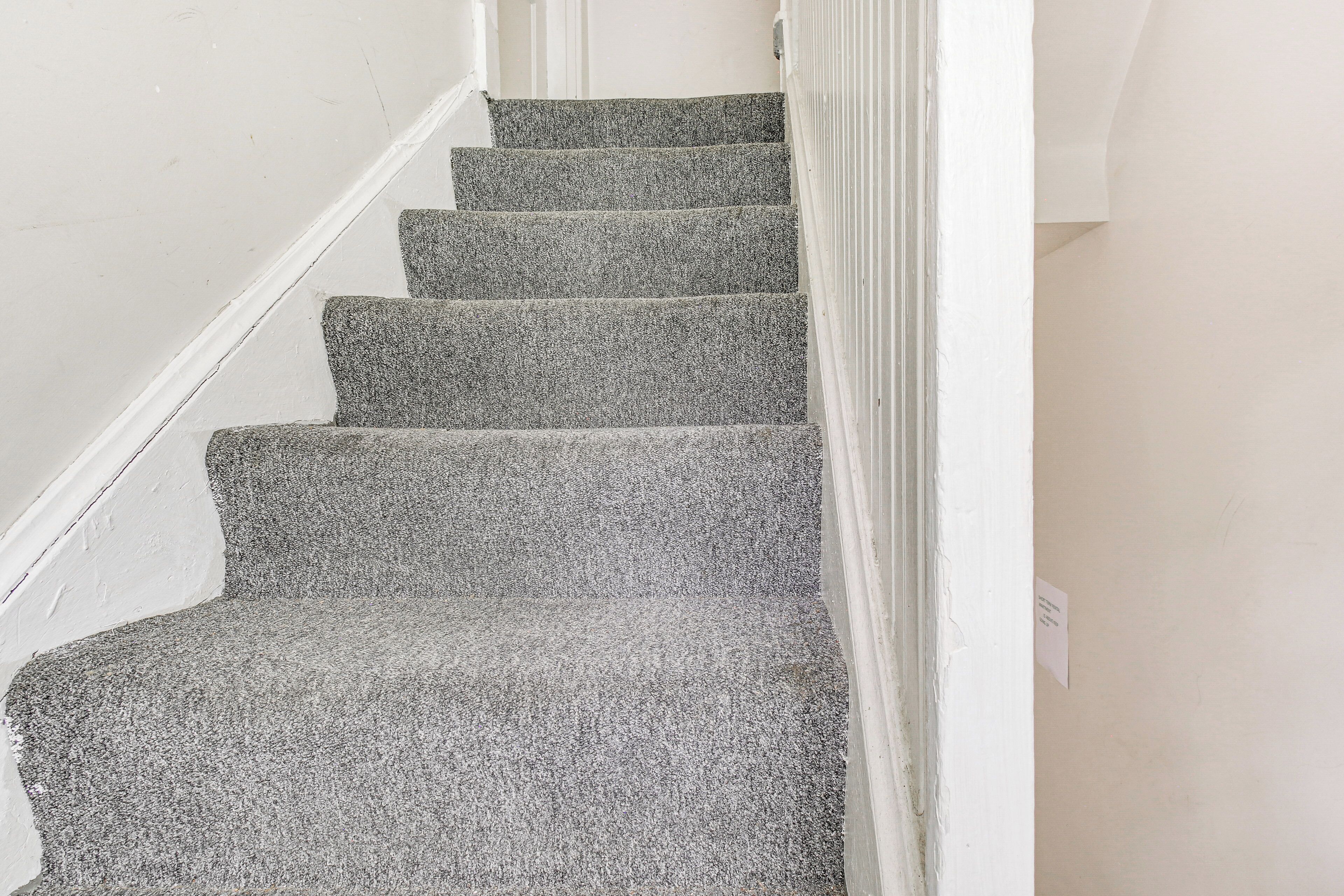 A staircase with carpeted steps leading to a landing.