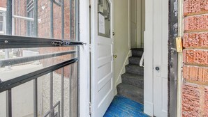 A narrow stairway leading to a white door with a brass doorknob. - Pet-friendly Cincinnati Apt: 5 Mi to Downtown! (Cincinnati)