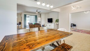 Ein geräumiger Essbereich mit einem großen Holztisch, weißen Wänden und moderner Pendelleuchte.