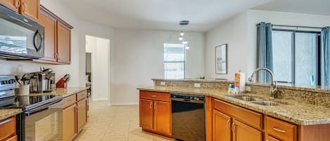 A kitchen with wooden cabinets, a stainless steel microwave, a dishwasher, and a granite countertop.