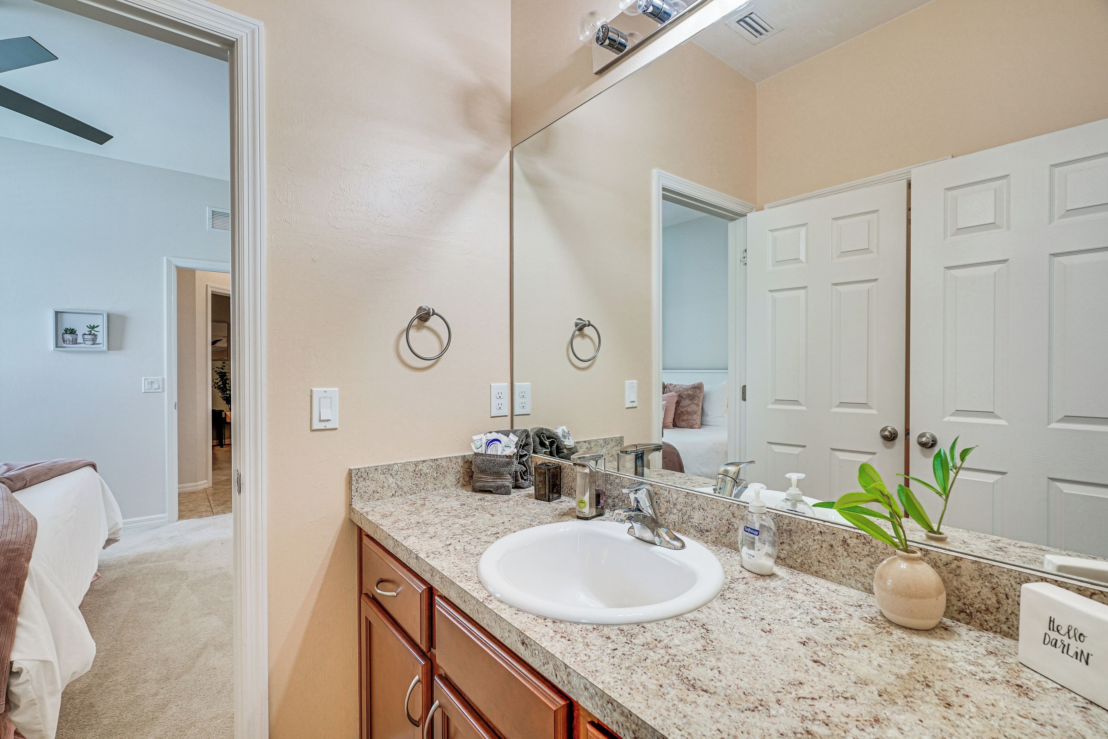 A bathroom with a white sink, a mirror, a towel rack, and a potted plant.