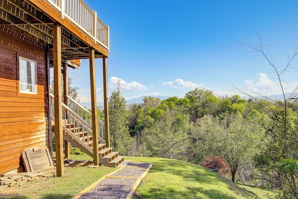A wooden cabin with a wooden deck and a staircase leading to a balcony.