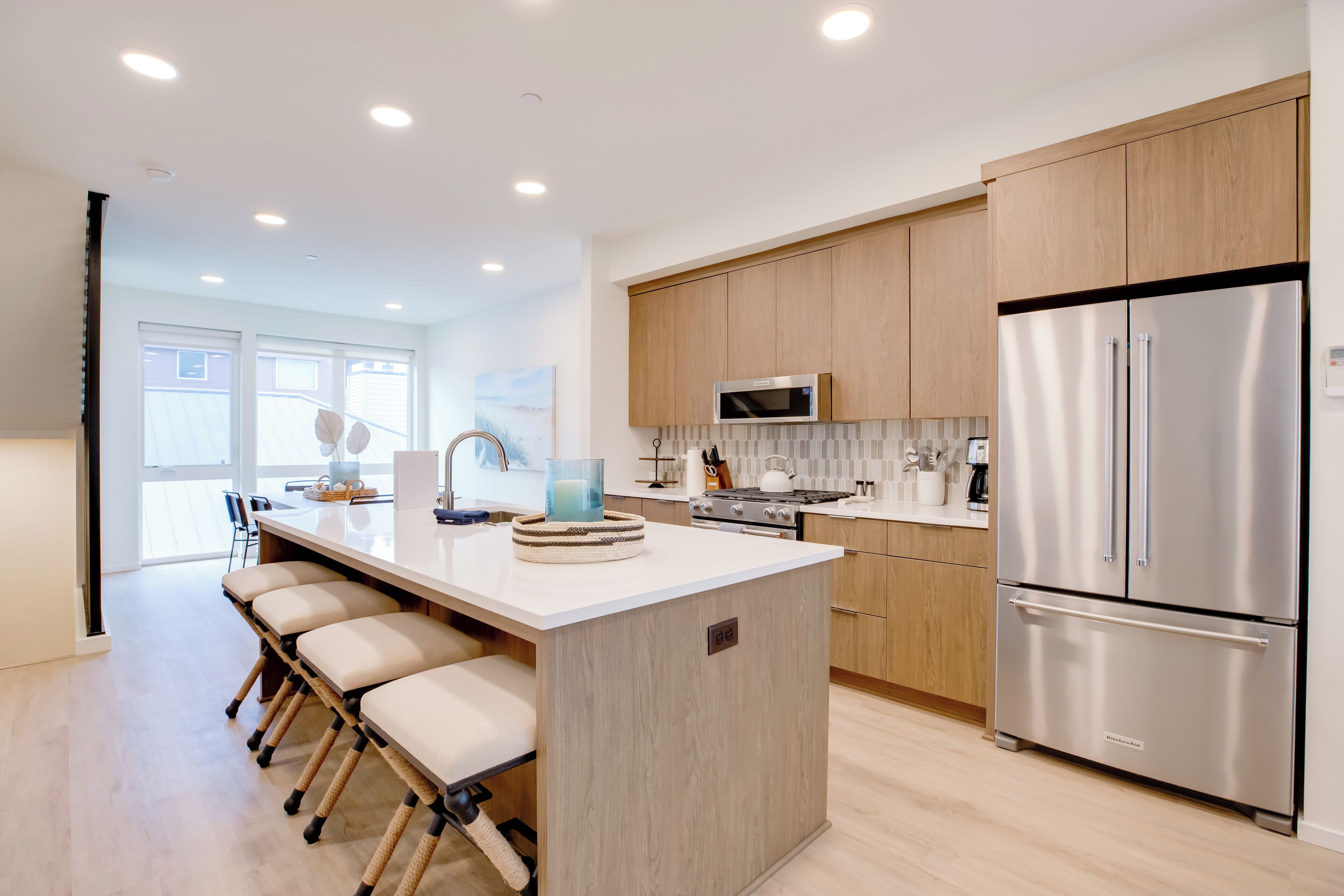 Una cocina moderna con una isla central, electrodomésticos de acero inoxidable y muebles de madera clara.