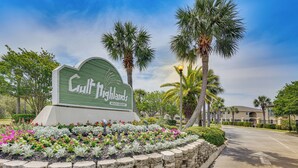 Señal de Gulf Highlands Beach Resort rodeada por un jardín ajardinado con diversas plantas y flores.