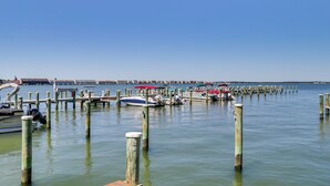 A marina with boats docked at wooden piers, calm water, and a clear sky.