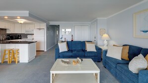 A modern living space with a kitchen, a blue sofa, and a white coffee table.