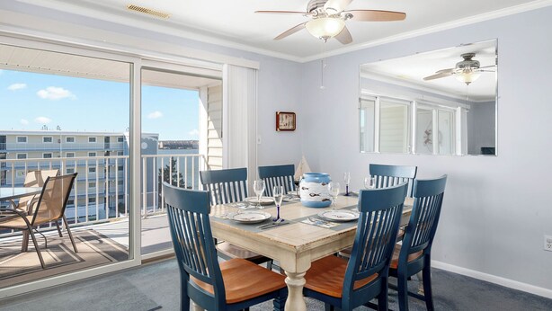 A dining area with a wooden table set for four, blue chairs, and a ceiling fan.