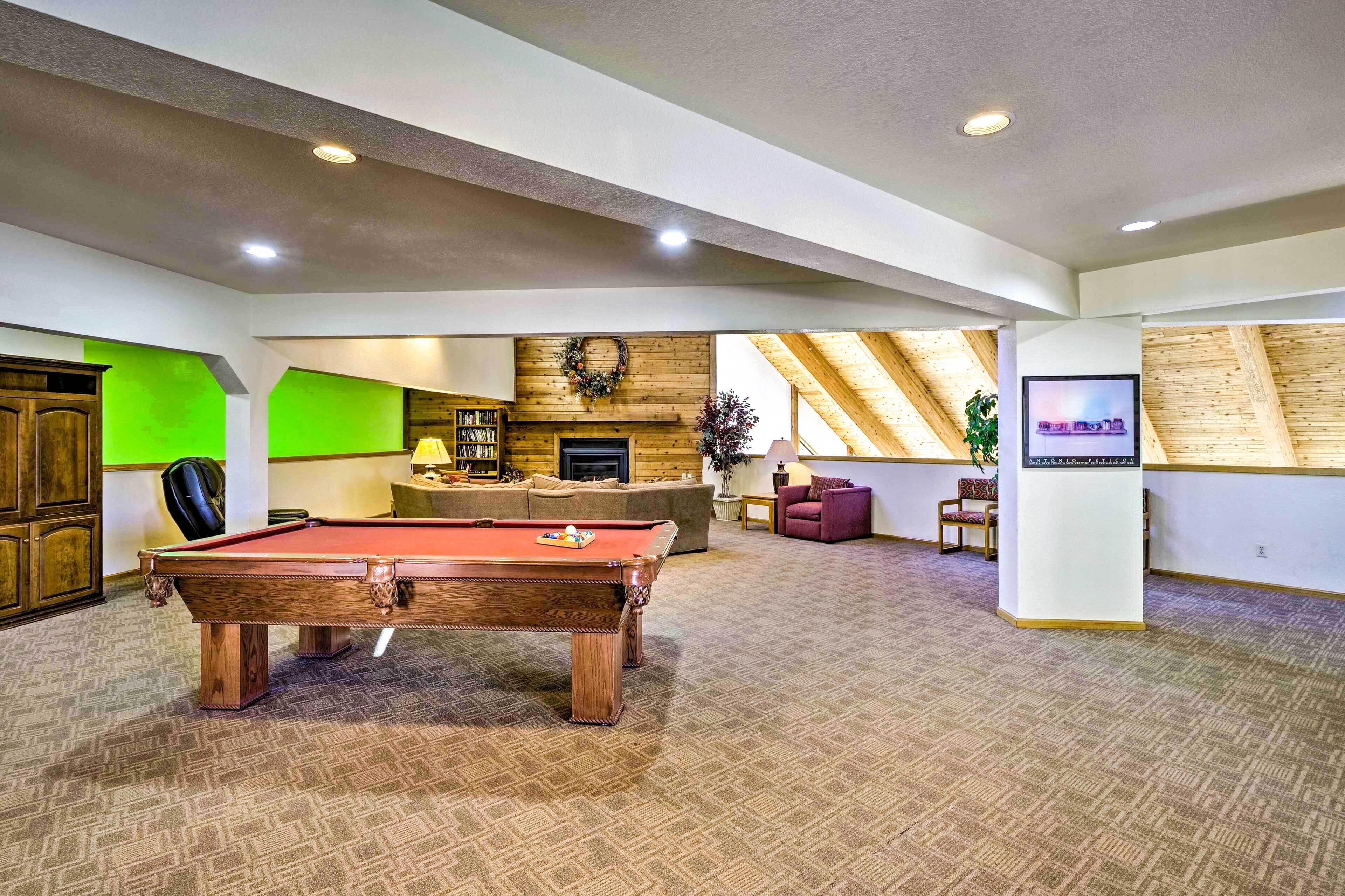 A spacious room with a pool table, a fireplace, and a television.