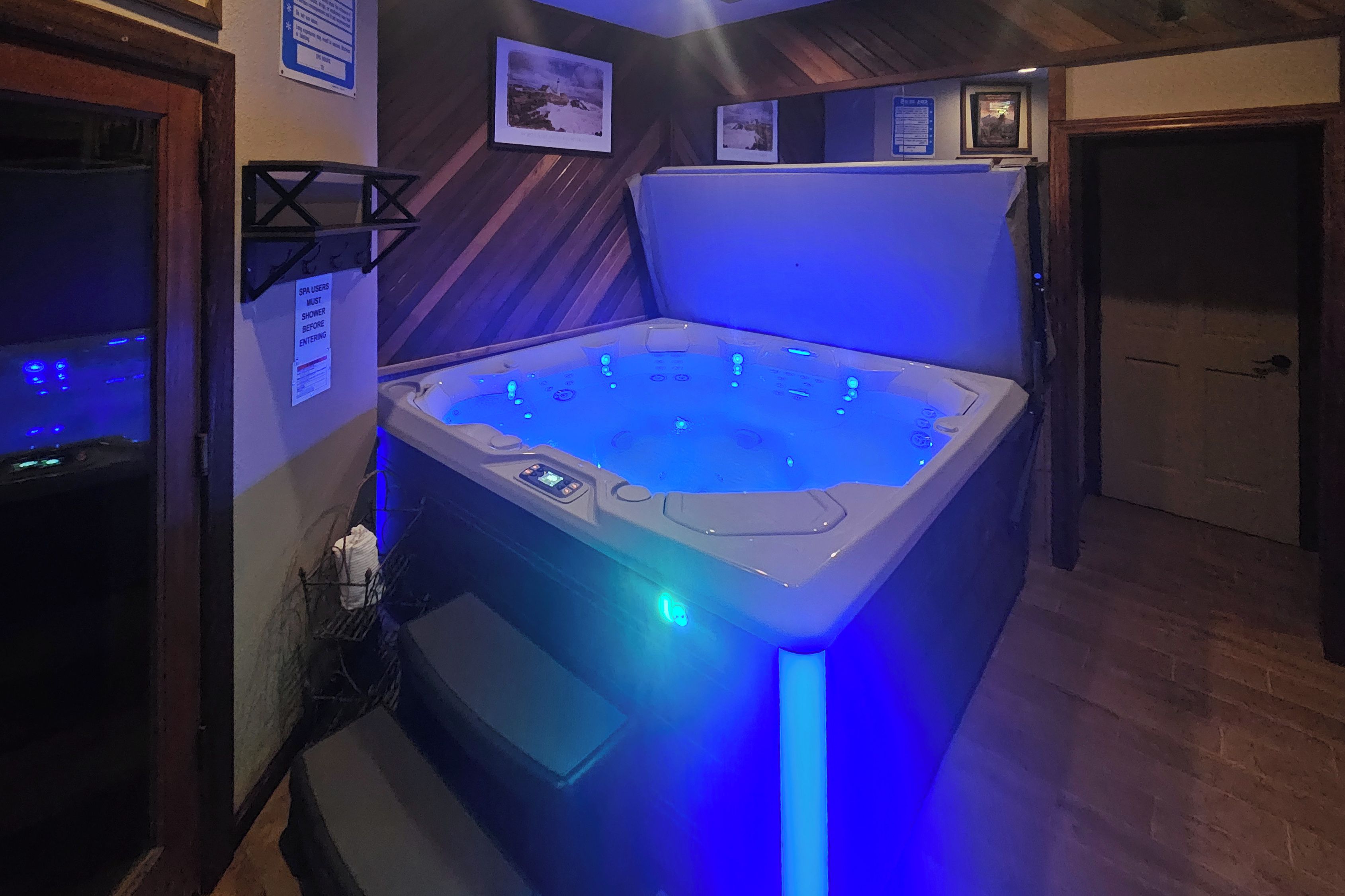 A spa area with a hot tub, a shower, and a sign indicating that spa users must shower before entering.