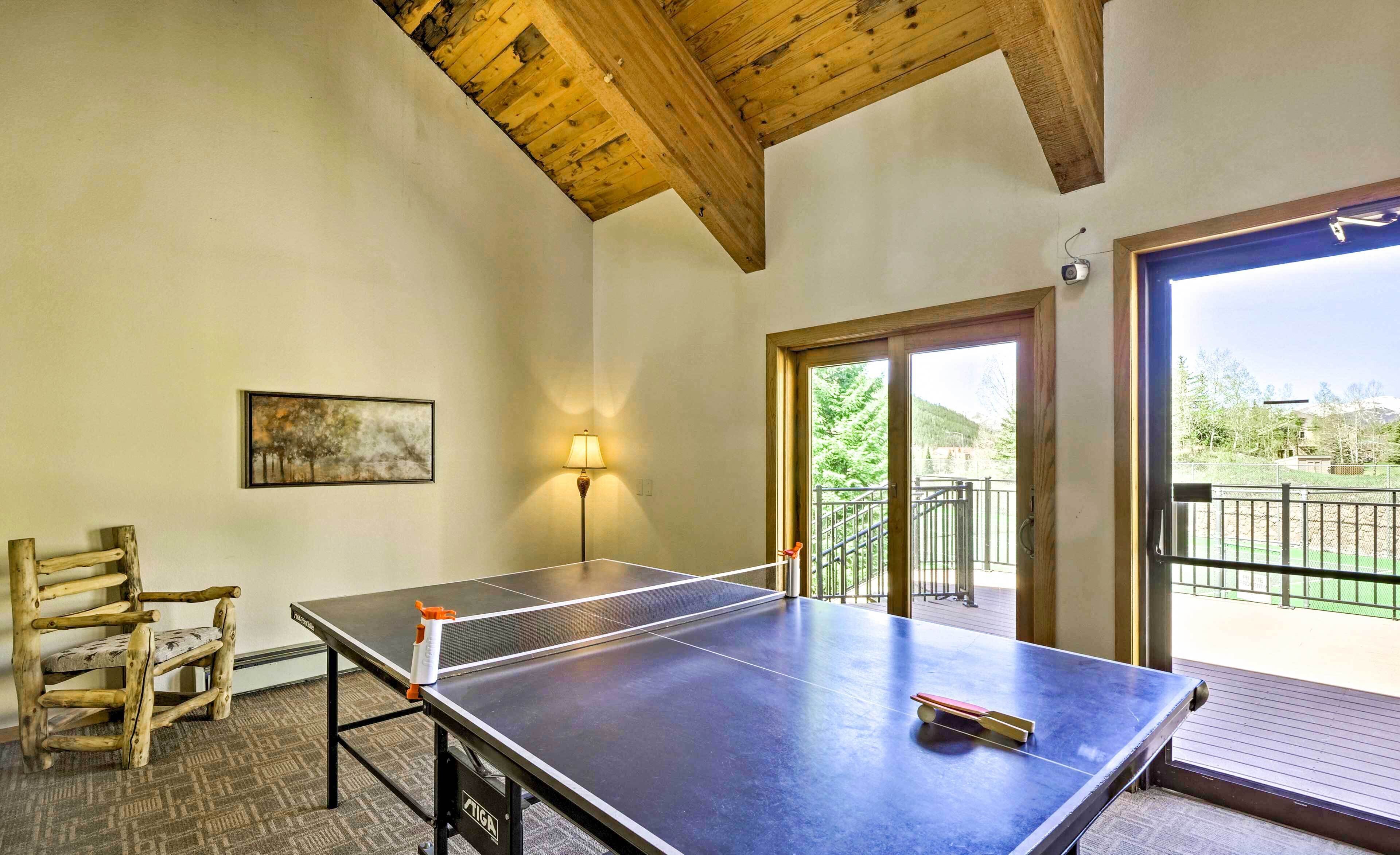 A ping pong table in a room with a wooden ceiling, a lamp, and a painting on the wall.