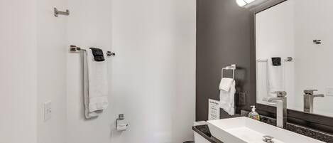 A modern bathroom with a white sink, a mirror, and a toilet.