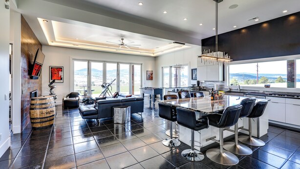 A modern kitchen with a large island, bar stools, and a view of the mountains. - Motorcycle-themed Home in Spearfish w/ Hot Tub! (Spearfish)