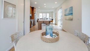 Una cucina moderna con isola centrale, una zona pranzo con tavolo rotondo e vista sull'area soggiorno.