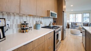 Una cucina moderna con mobili in legno, piano cottura in acciaio inossidabile e forno a microonde.