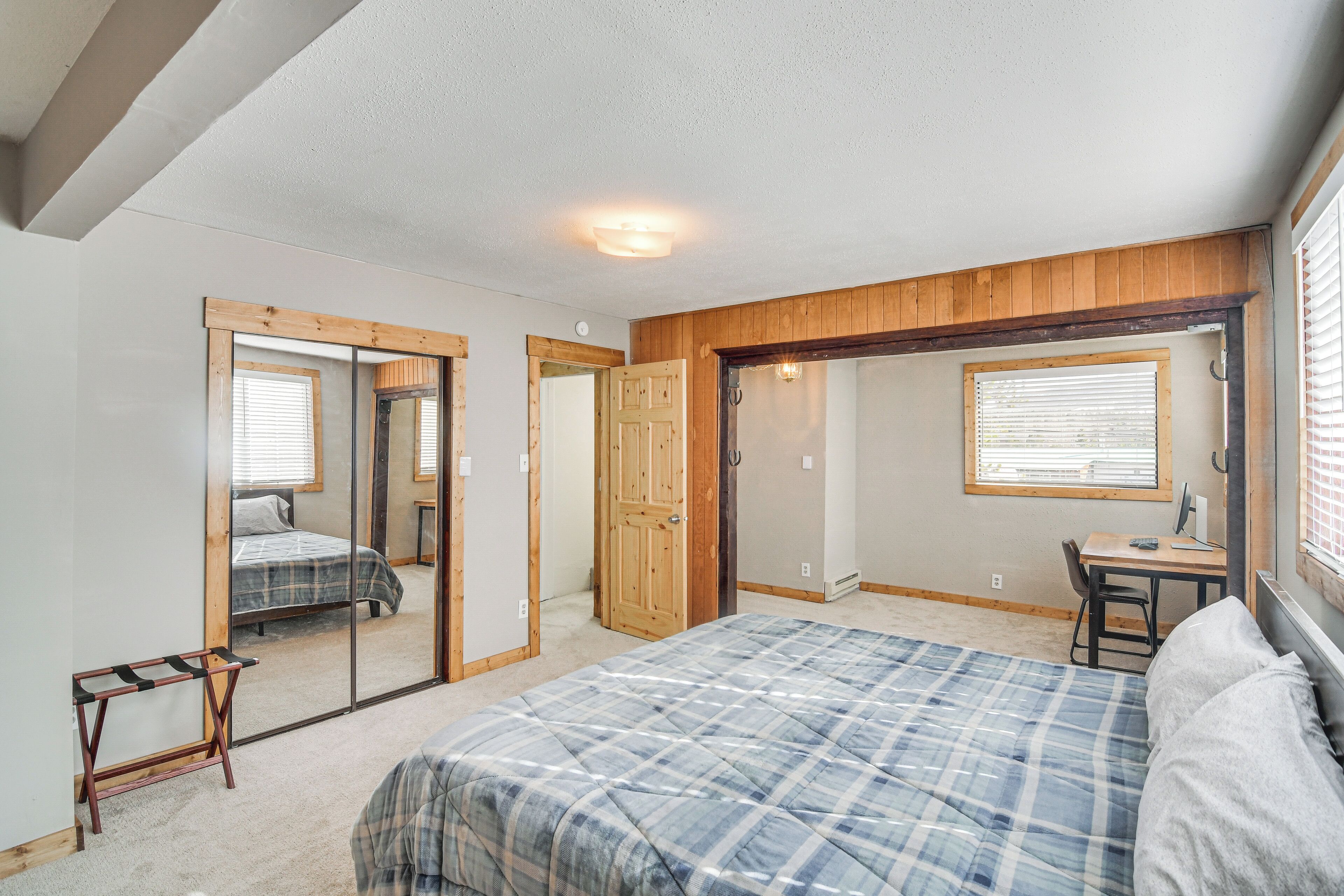 Ein Schlafzimmer mit Bett, Schreibtisch und Stuhl. Eine Tür führt in einen weiteren Raum.