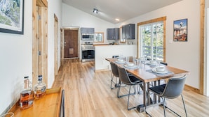 Una cucina moderna con mobili in legno, un tavolo da pranzo per quattro persone e un'ampia finestra che offre luce naturale.