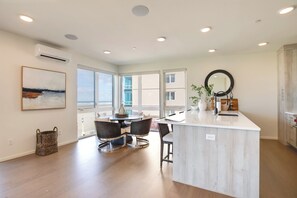 A modern kitchen with a central island, large windows, and a dining area with chairs.