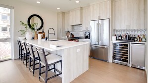 Una cocina moderna con una isla central, electrodomésticos de acero inoxidable y un enfriador de vino.