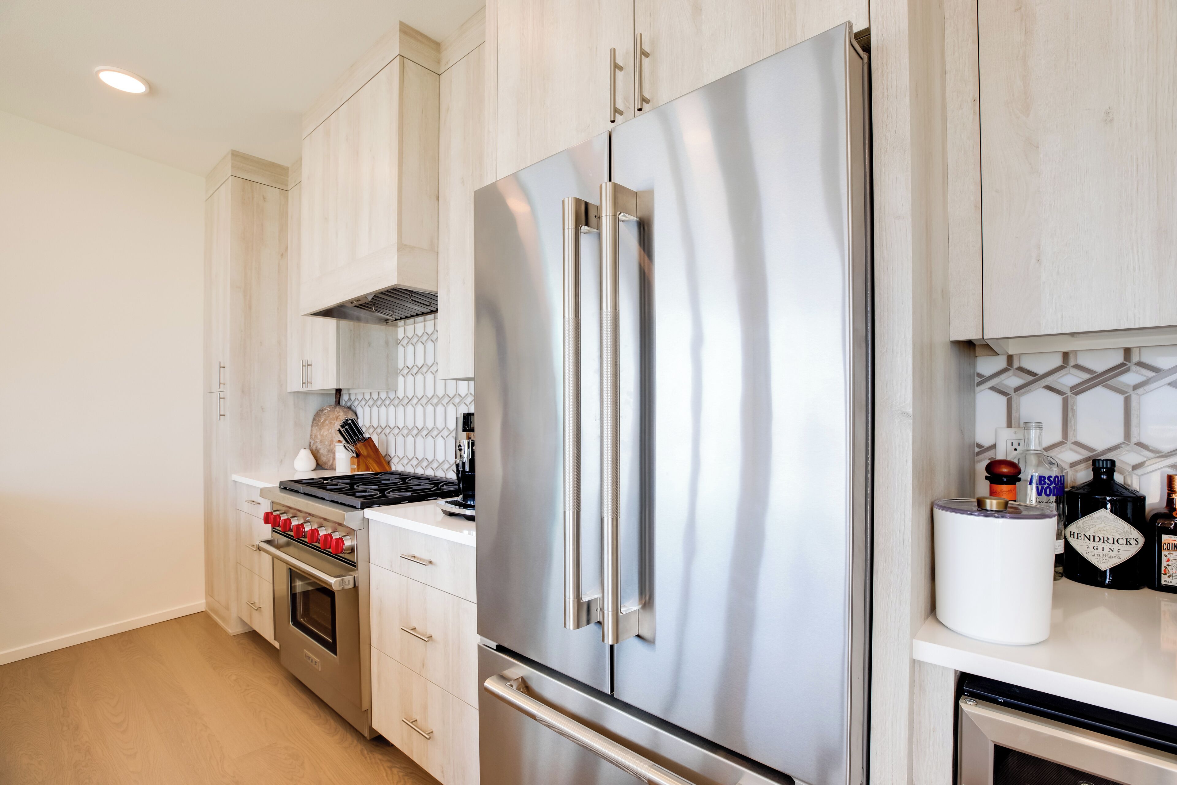 Een moderne keuken met roestvrijstalen apparatuur, houten kastjes en een betegelde spatwand.