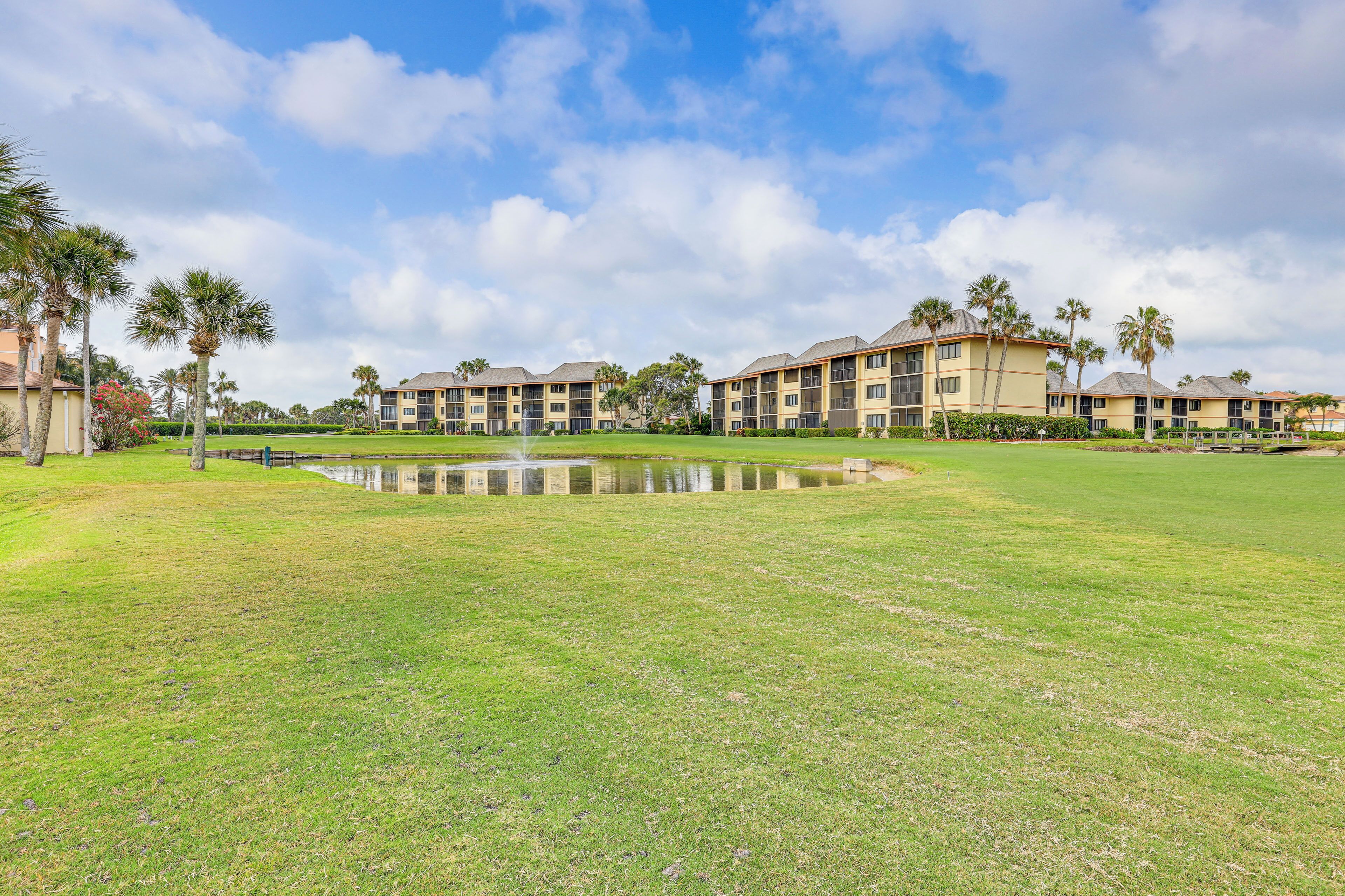 A hotel with multiple buildings, a central courtyard with a fountain, and palm trees.