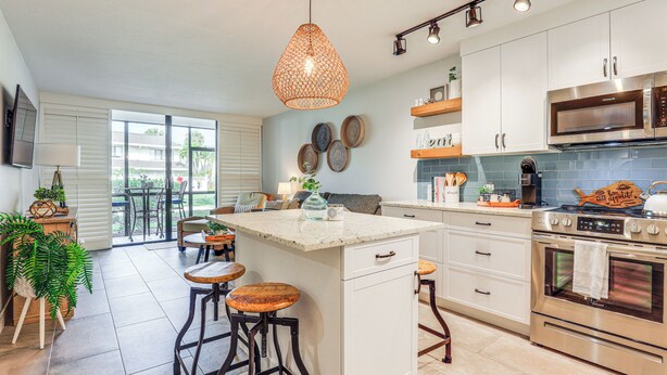 A modern kitchen with a large island, stainless steel appliances, and a dining area with stools.