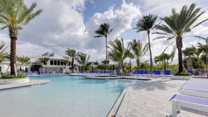 A swimming pool with blue lounge chairs and palm trees.