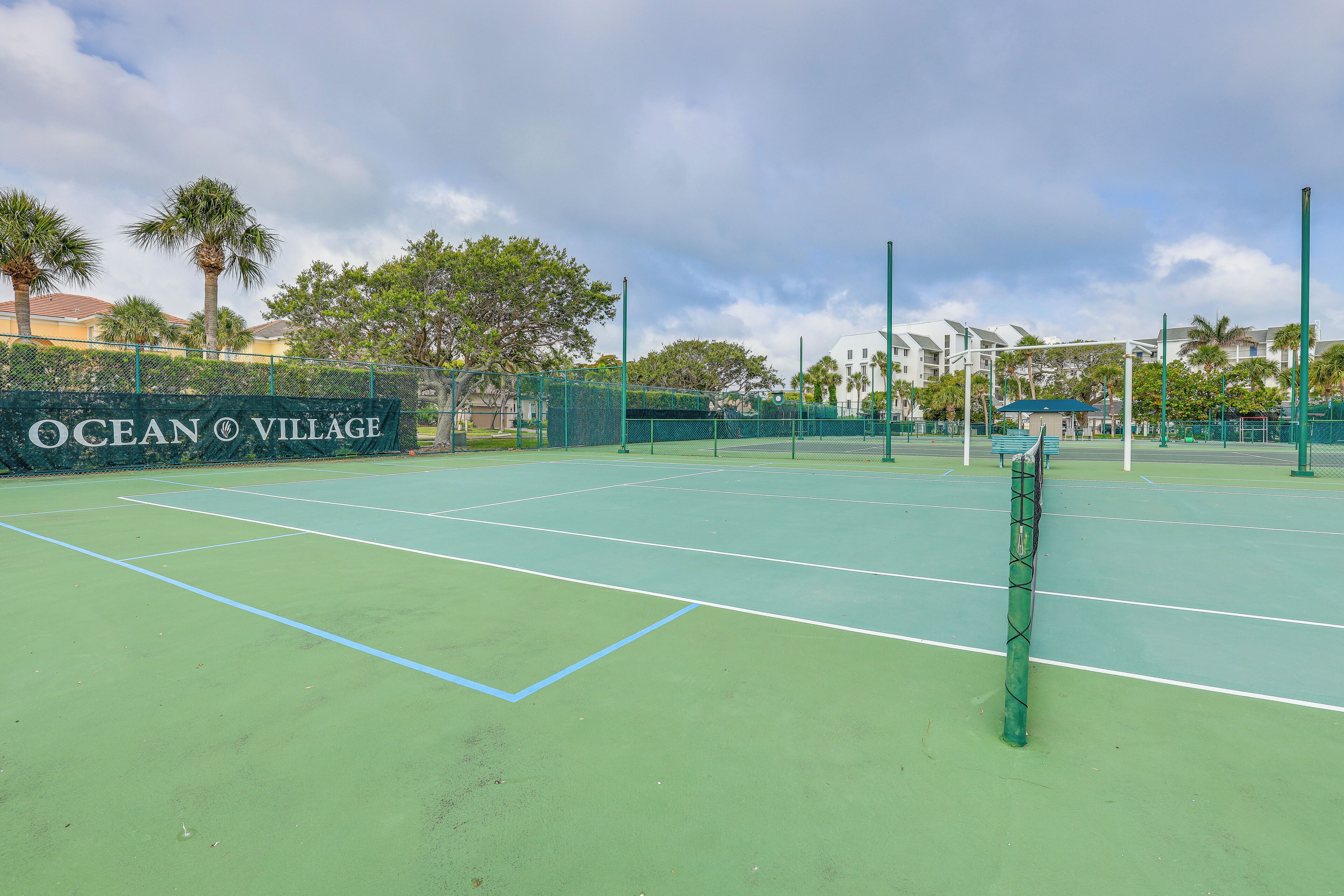 A tennis court with a sign reading "Ocean Village."