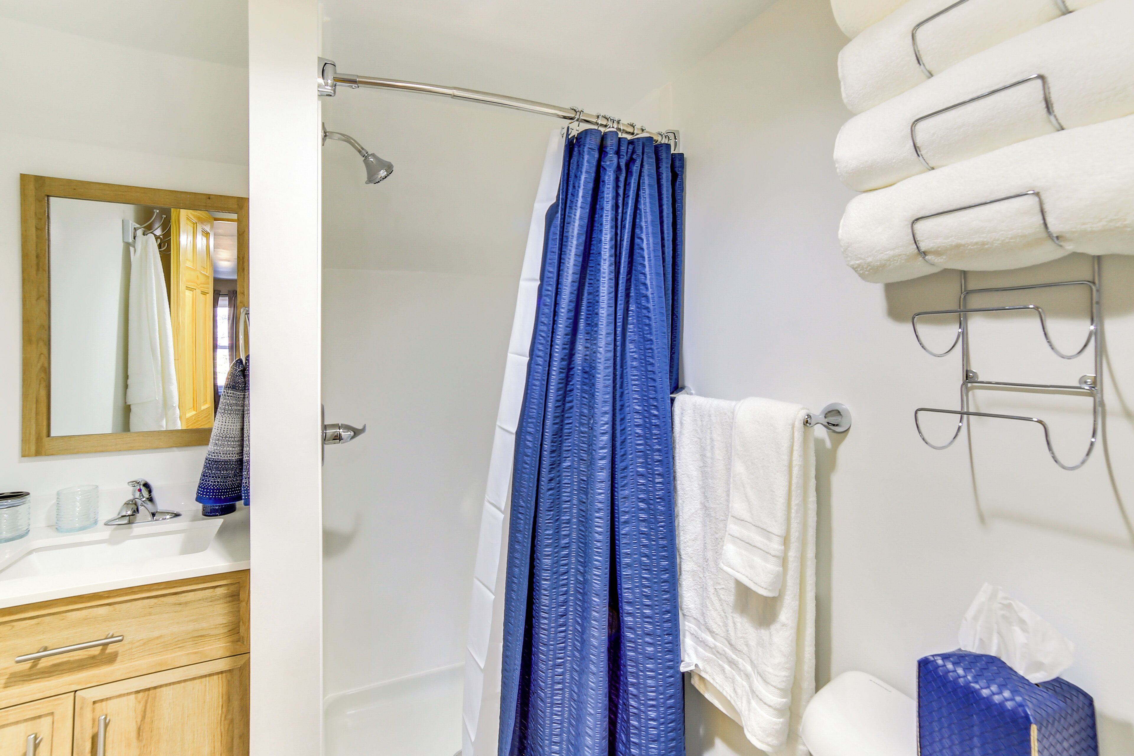 A bathroom with a shower, a sink, a mirror, and a towel rack.
