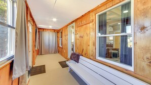 Een houten interieur met een bank, grote ramen en uitzicht op het buiten.
