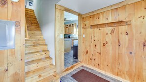 Een houten trap die leidt naar een keuken met houten wanden en kasten.