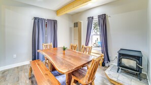 Een eethoek met een houten tafel en stoelen, een kleine potplant en een houtkachel.