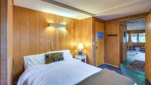Een kamer met houten lambrisering, een bed, een nachtkastje met lamp en een deur die leidt naar een balkon.